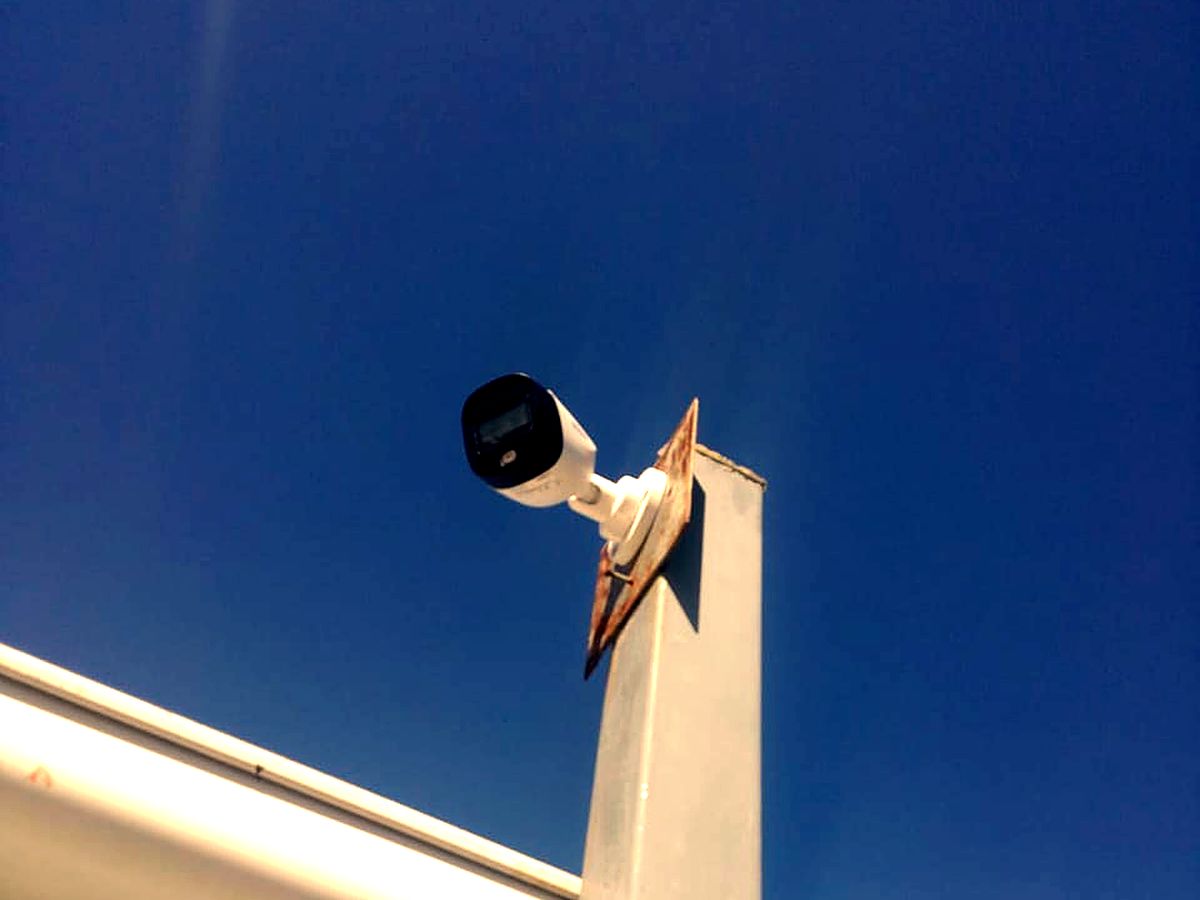 Outdoor bullet CCTV camera mounted on a bracket against a blue sky
