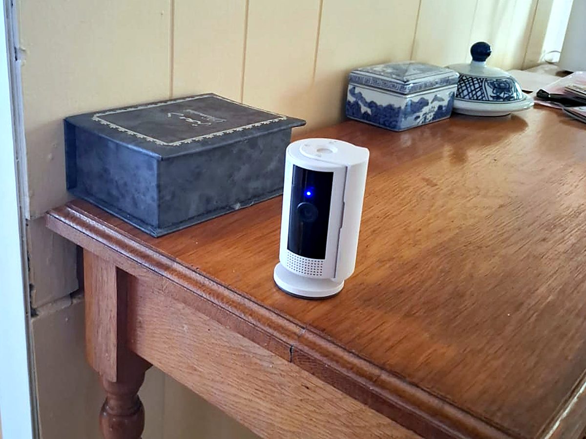 White Ring indoor security camera on a wooden side table in a home