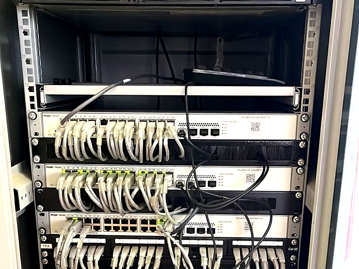 Full-height server rack with several patch panels and switches cabled with white network leads